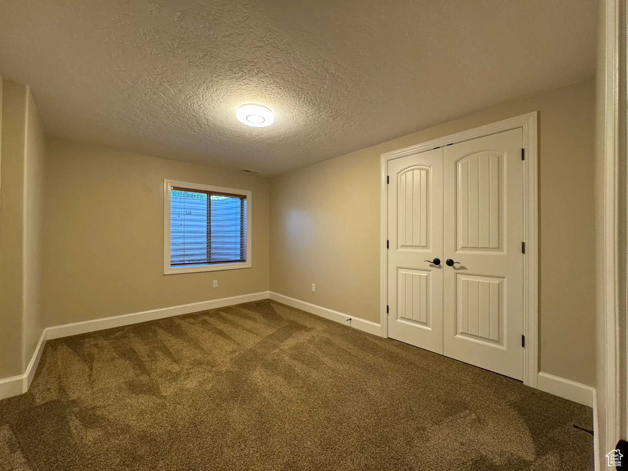 Unfurnished bedroom featuring carpet, a textured ceiling, and a closet