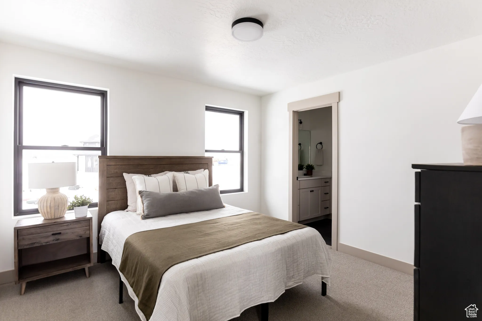 Bedroom featuring carpet floors, ensuite bathroom, and a textured ceiling