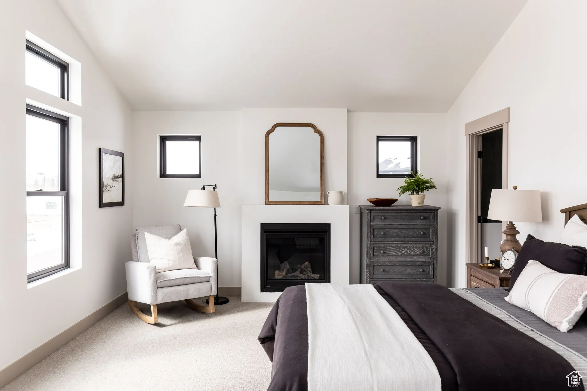 Bedroom featuring lofted ceiling, a glass covered fireplace, and carpet