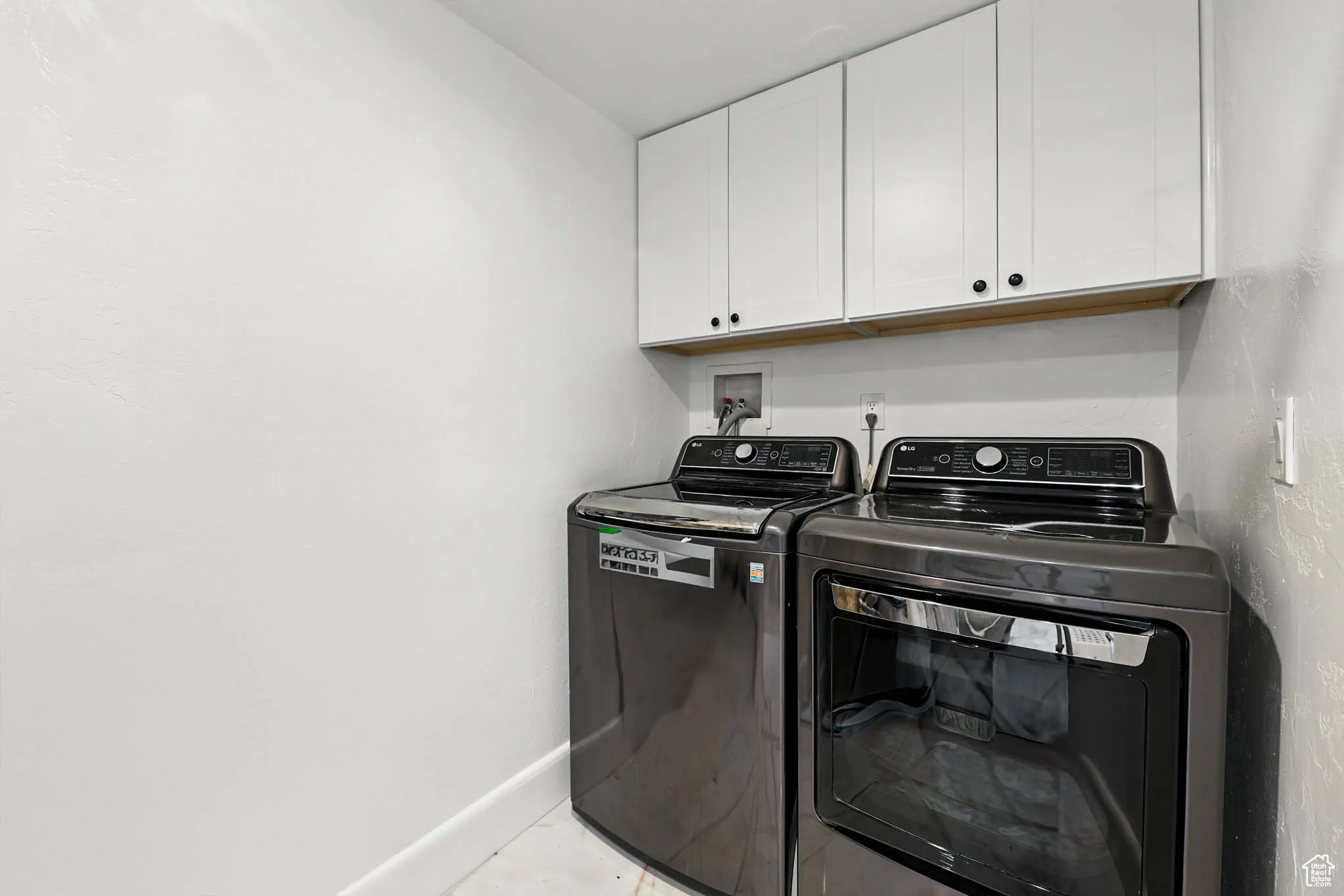 Laundry room featuring cabinet space, separate washer and dryer, and light tile patterned floors