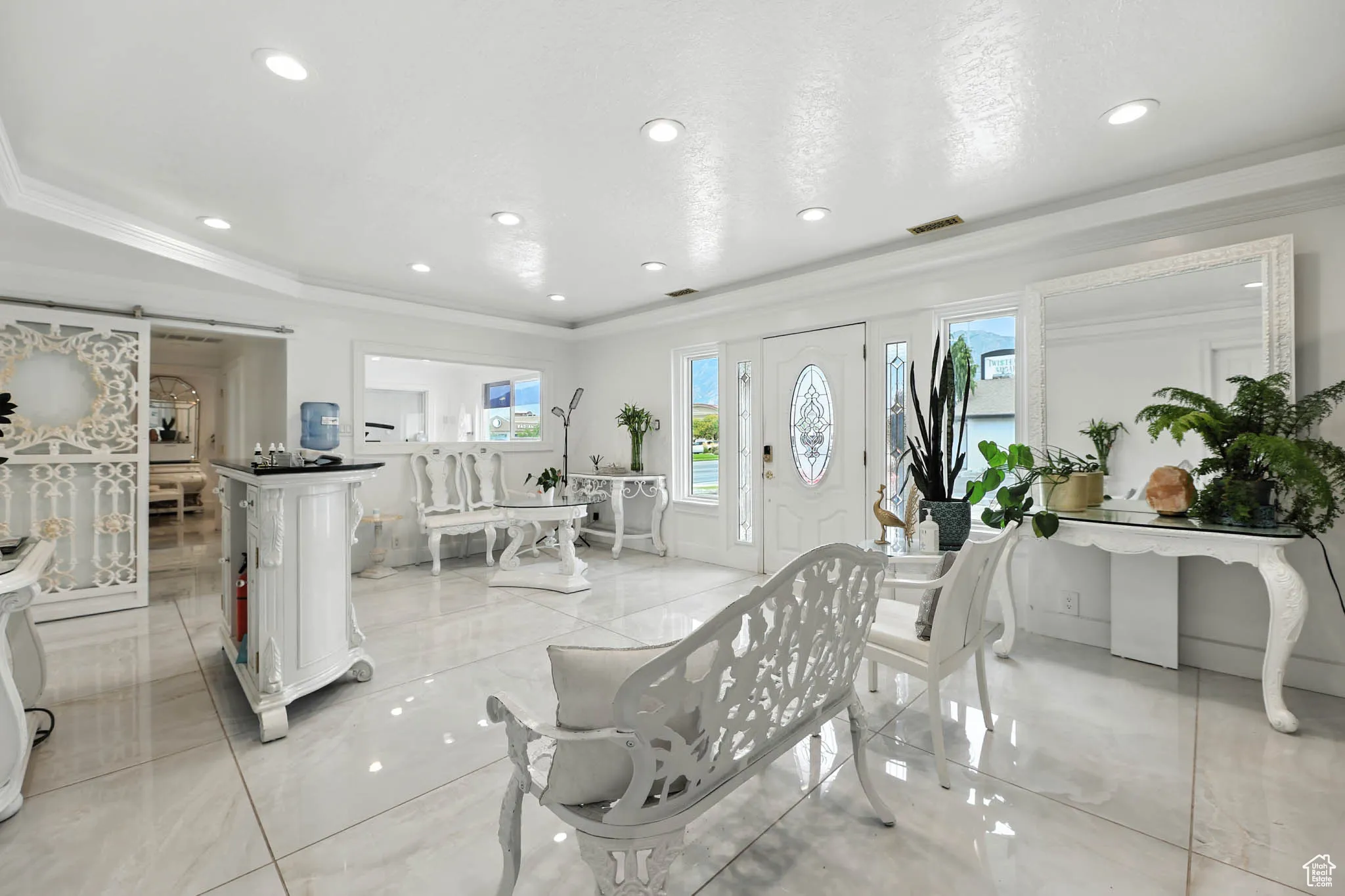 Foyer entrance with a barn door, ornamental molding, recessed lighting, and light marble finish floors