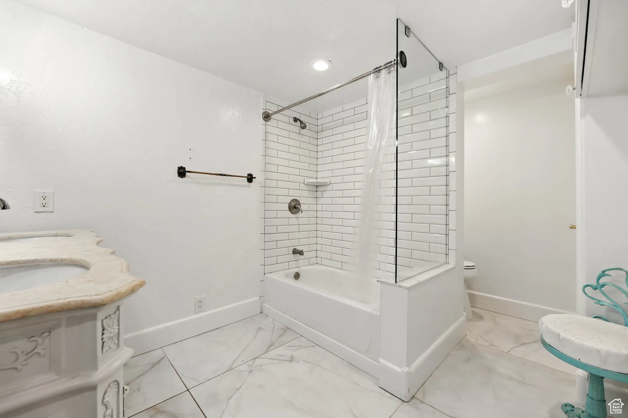 Bathroom featuring shower / bath combination with curtain, double vanity, light marble finish floors, and recessed lighting