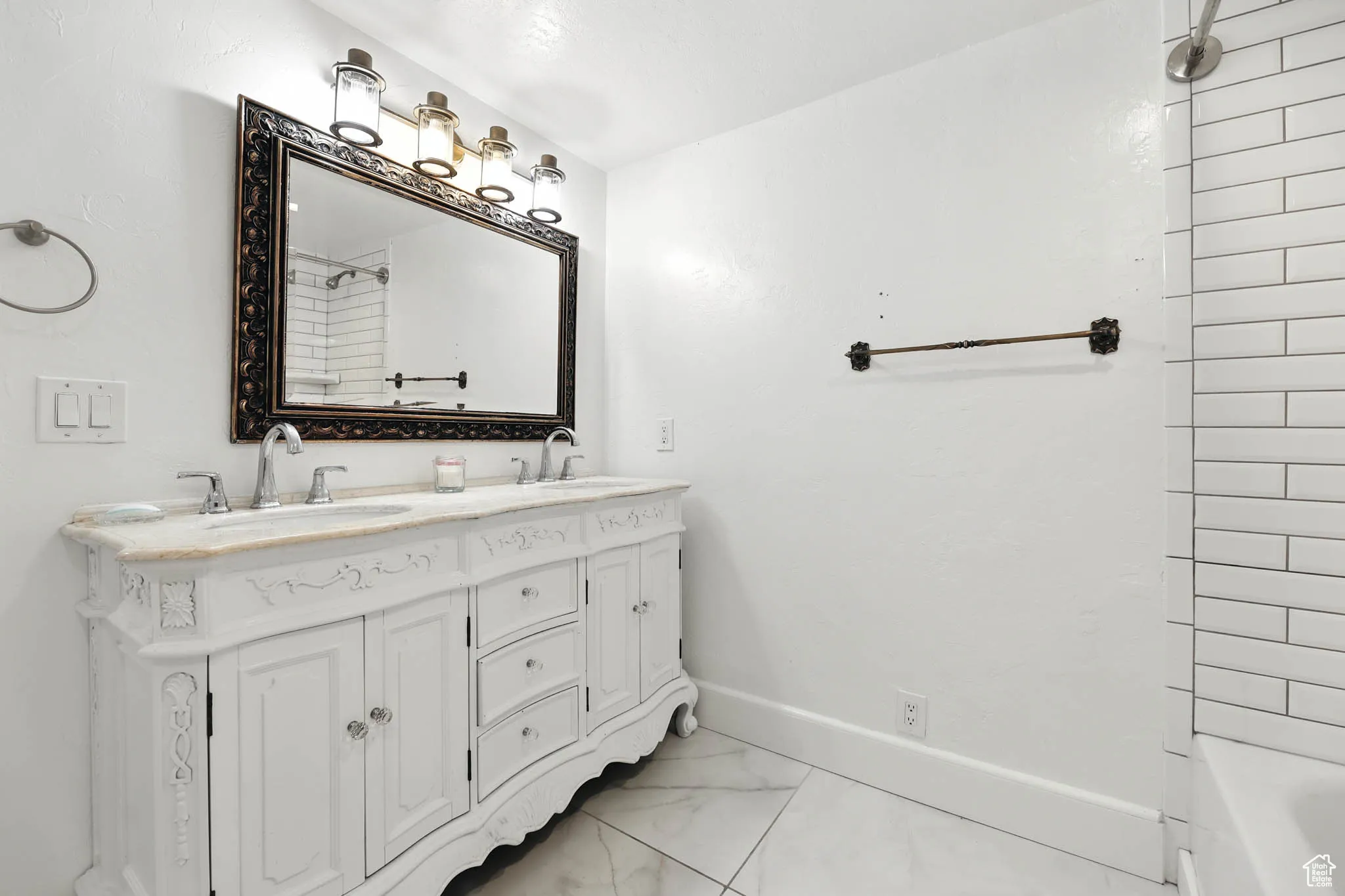 Full bathroom featuring double vanity, light marble finish floors, and tub / shower combination