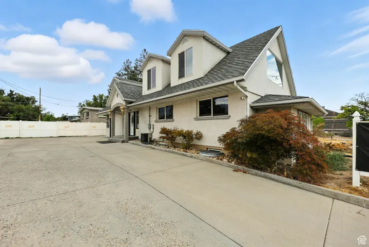 View of property exterior featuring stucco siding, a shingled roof, and driveway