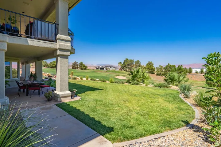 View of green lawn featuring a balcony, a mountain view, a patio, and golf course view