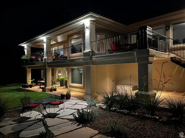 Back of house at twilight with a patio, stucco siding, and a balcony