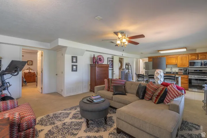 Living area with light carpet, ceiling fan, and a textured ceiling