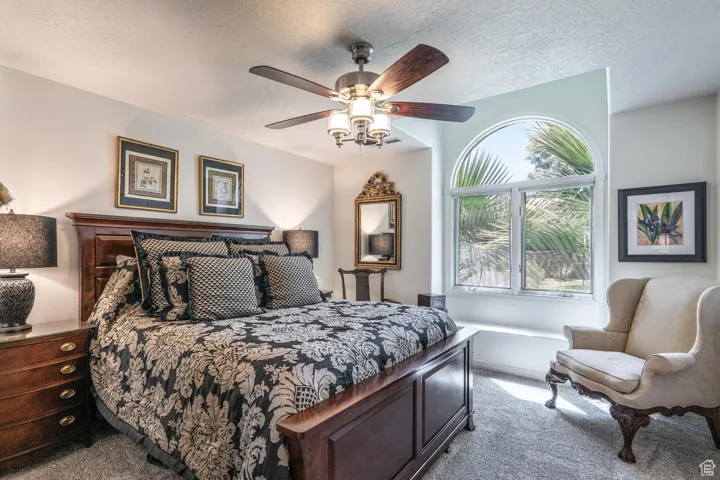 Carpeted bedroom with a textured ceiling and ceiling fan