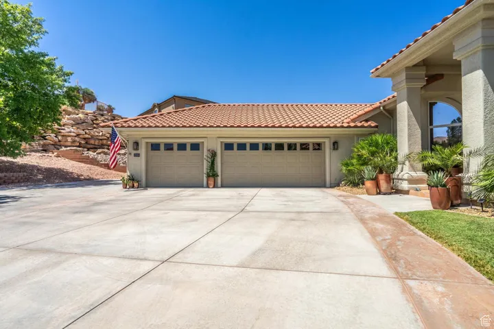 View of front of property featuring a garage, driveway, a tile roof, and stucco siding