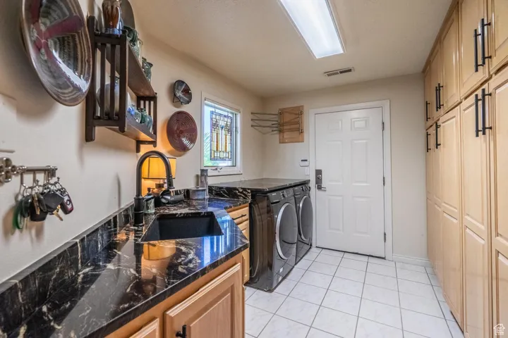 Laundry room featuring light tile patterned floors, washing machine and clothes dryer, and cabinet space