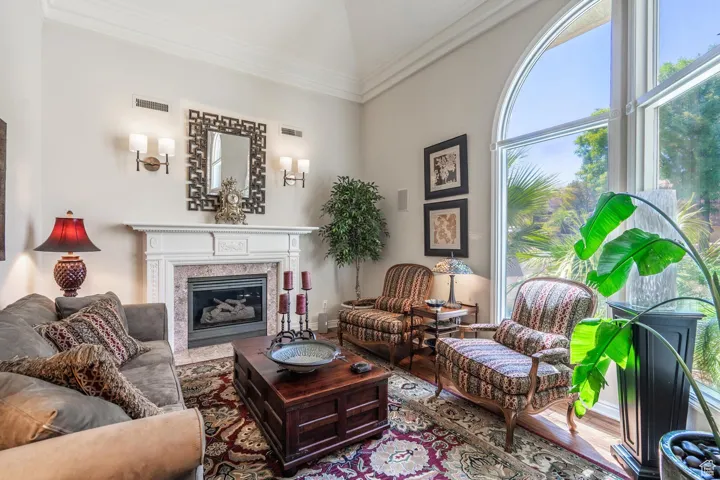 Living area with ornamental molding, a high end fireplace, and wood finished floors