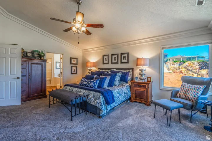 Bedroom featuring crown molding, lofted ceiling, carpet flooring, a textured ceiling, and a ceiling fan