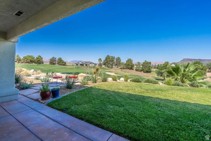 View of green lawn with a patio, golf course view, and a mountain view