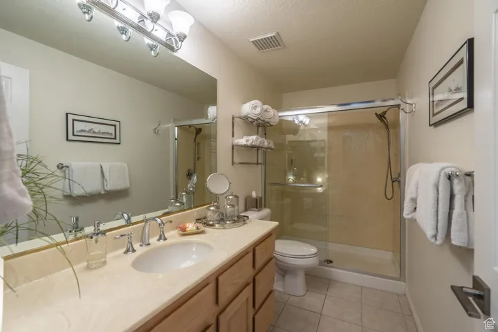 Bathroom featuring light tile patterned floors, vanity, a stall shower, and a textured ceiling