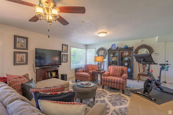 Living area with carpet, a textured ceiling, and ceiling fan