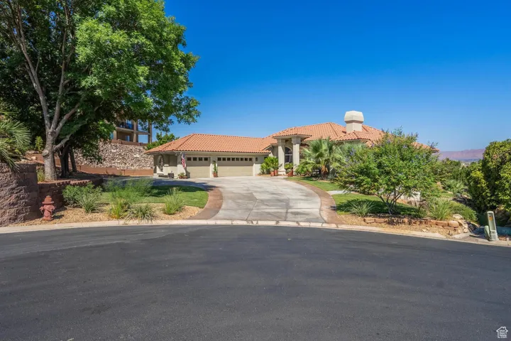 Mediterranean / spanish-style home with an attached garage, concrete driveway, a tile roof, and stucco siding