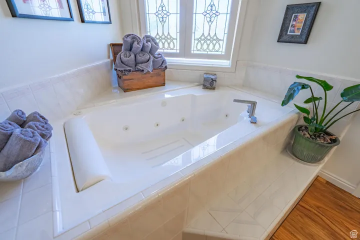 Full bathroom featuring a tub with jets and wood finished floors