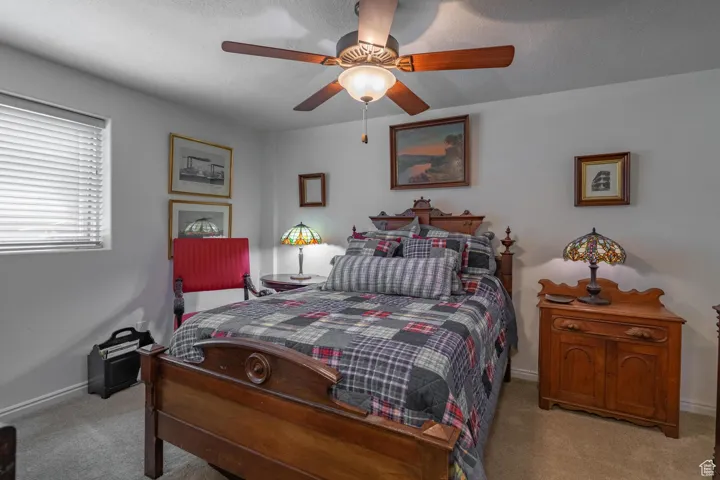 Carpeted bedroom featuring a textured ceiling and ceiling fan
