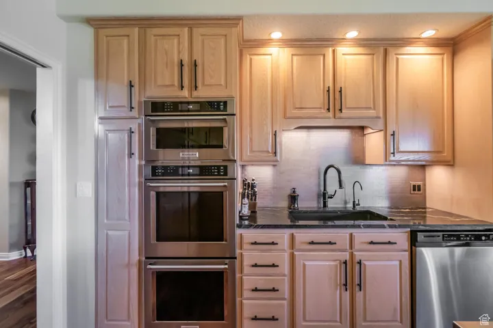 Kitchen with appliances with stainless steel finishes, decorative backsplash, dark stone countertops, recessed lighting, and dark wood-style floors