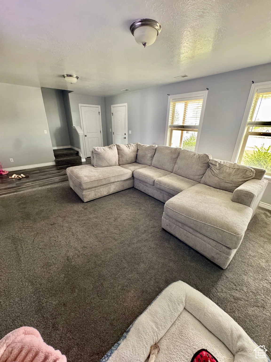 Carpeted living area featuring a textured ceiling and baseboards