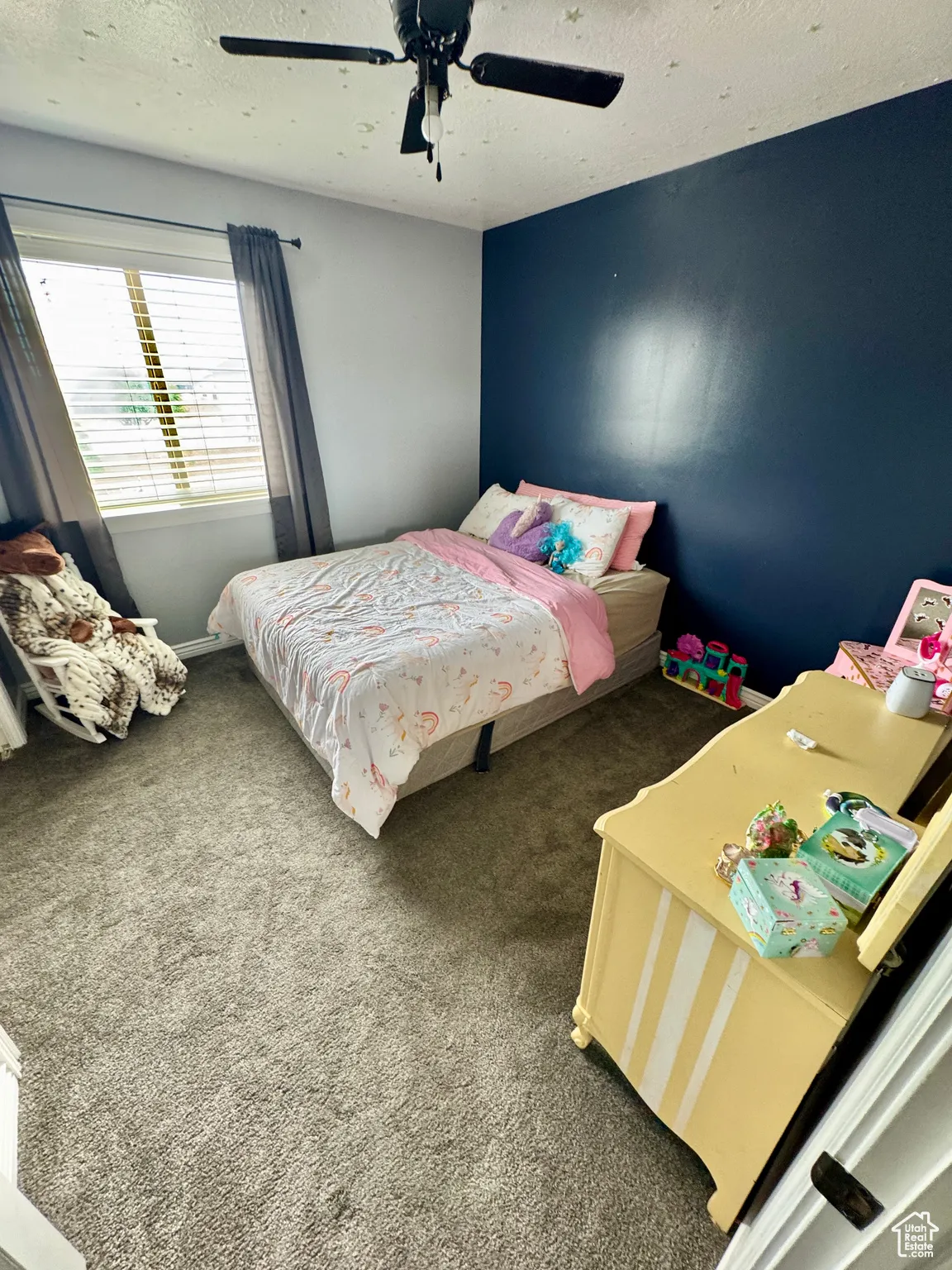 Carpeted bedroom with ceiling fan and a textured ceiling