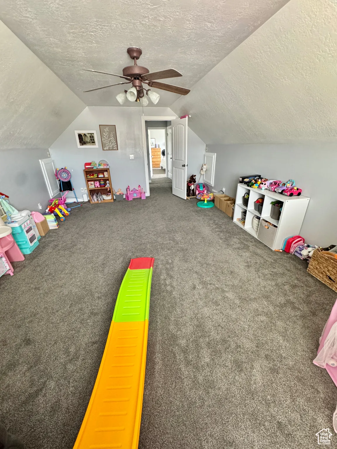 Rec room with a textured ceiling, carpet flooring, lofted ceiling, and a ceiling fan