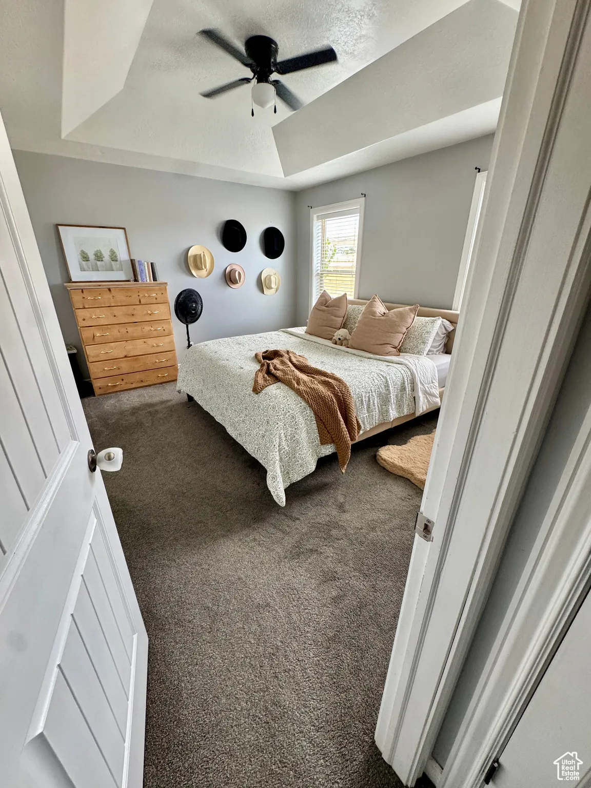 Bedroom with a tray ceiling, a textured ceiling, carpet floors, and ceiling fan