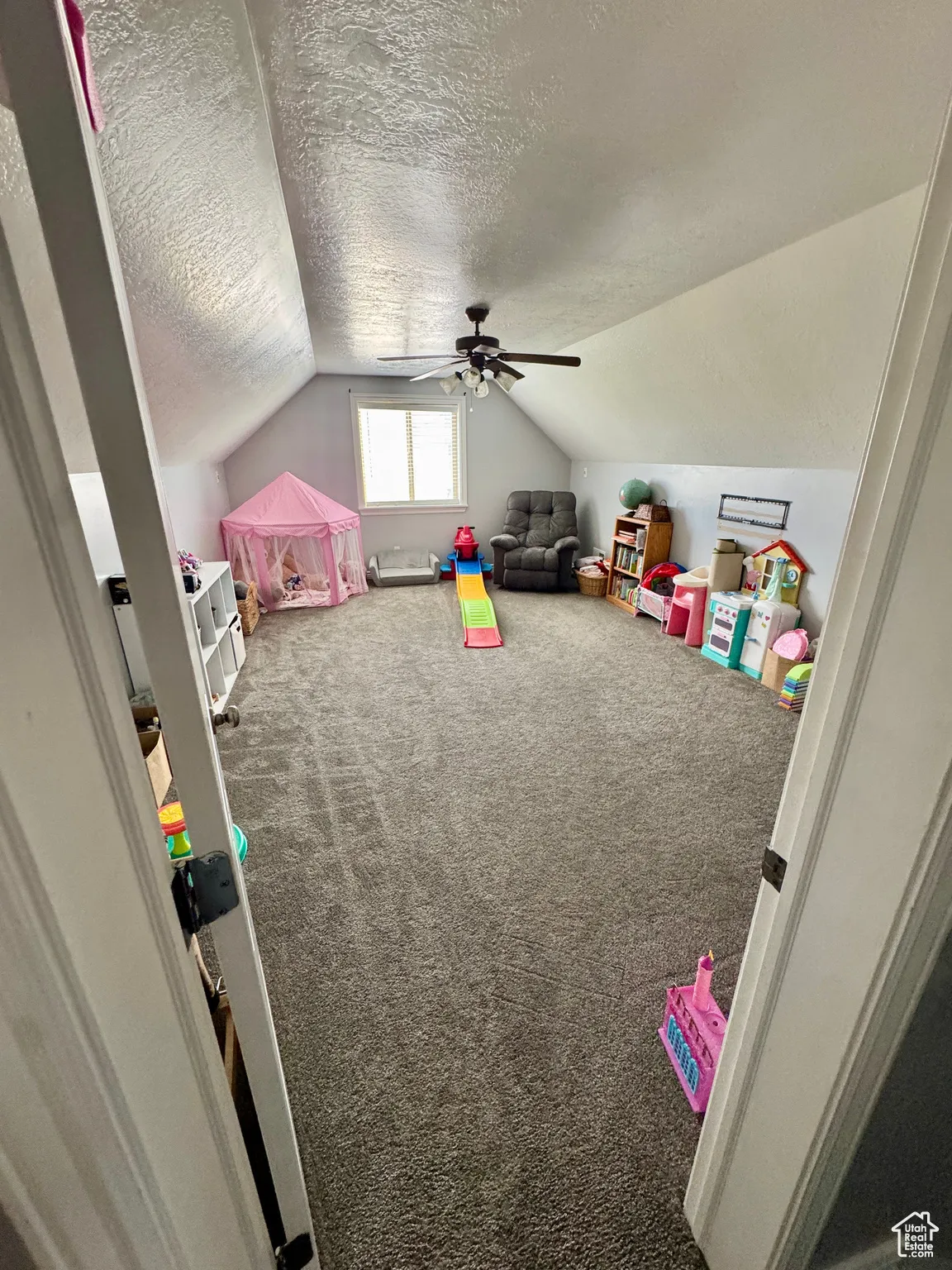Playroom with carpet, a textured ceiling, lofted ceiling, and a ceiling fan