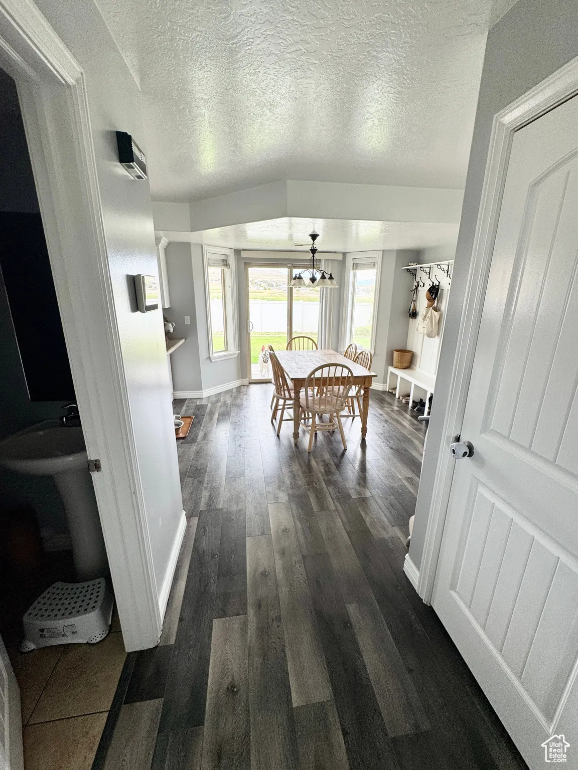 Hallway with a textured ceiling, dark wood-style flooring, and a chandelier