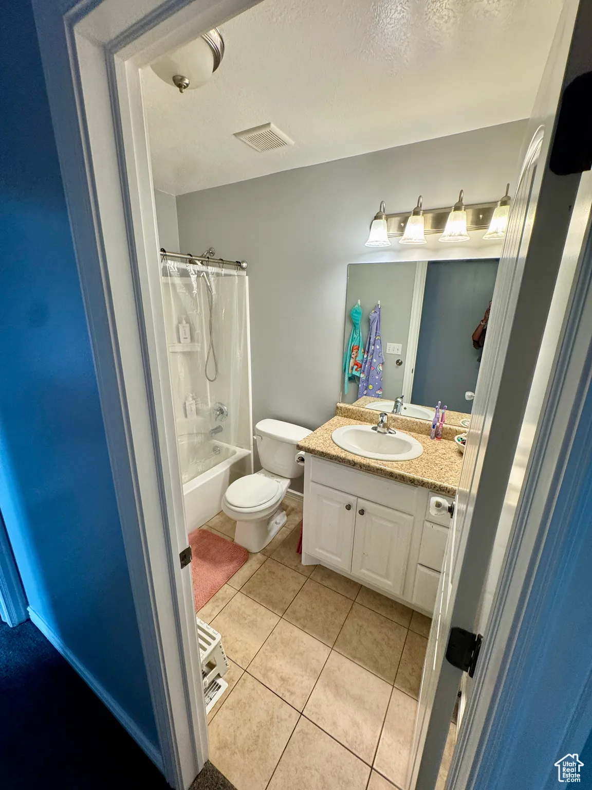 Bathroom with shower / bath combo, light tile patterned floors, vanity, and a textured ceiling