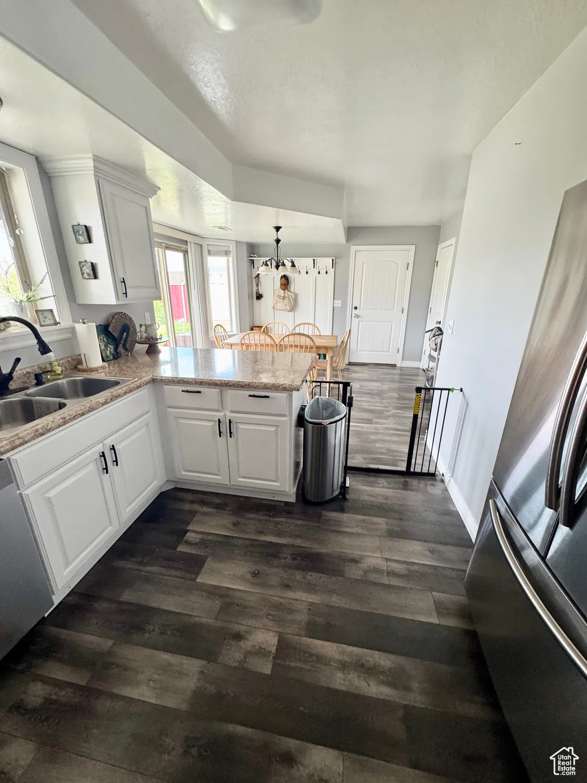 Kitchen with stainless steel appliances, a peninsula, dark wood finished floors, and white cabinetry