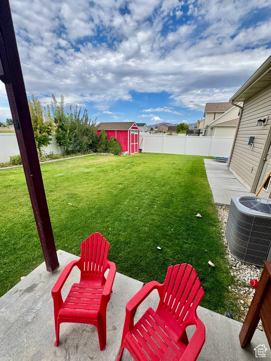 Fenced backyard with a storage unit and a patio area