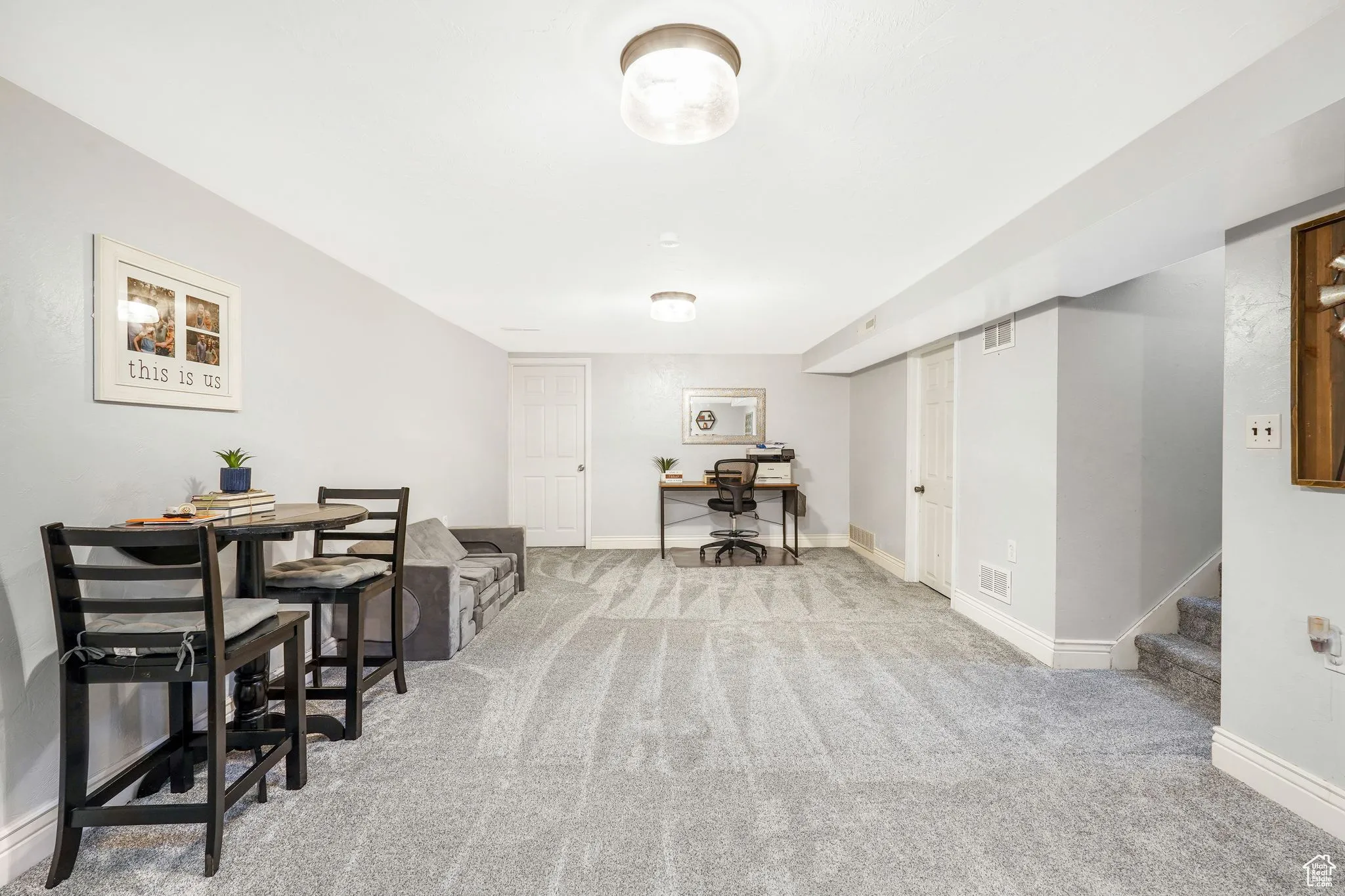 Dining space with a desk, light carpet, and stairs