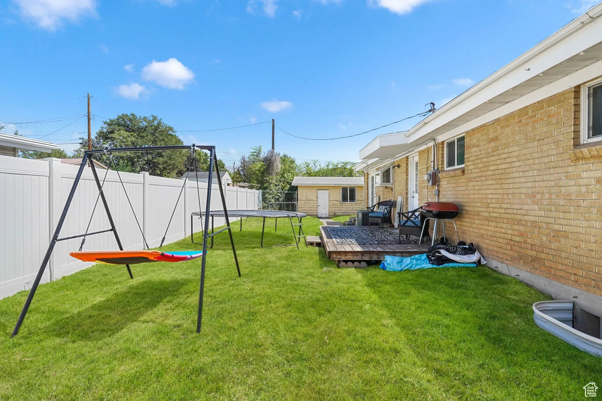 Fenced backyard with a trampoline and a wooden deck