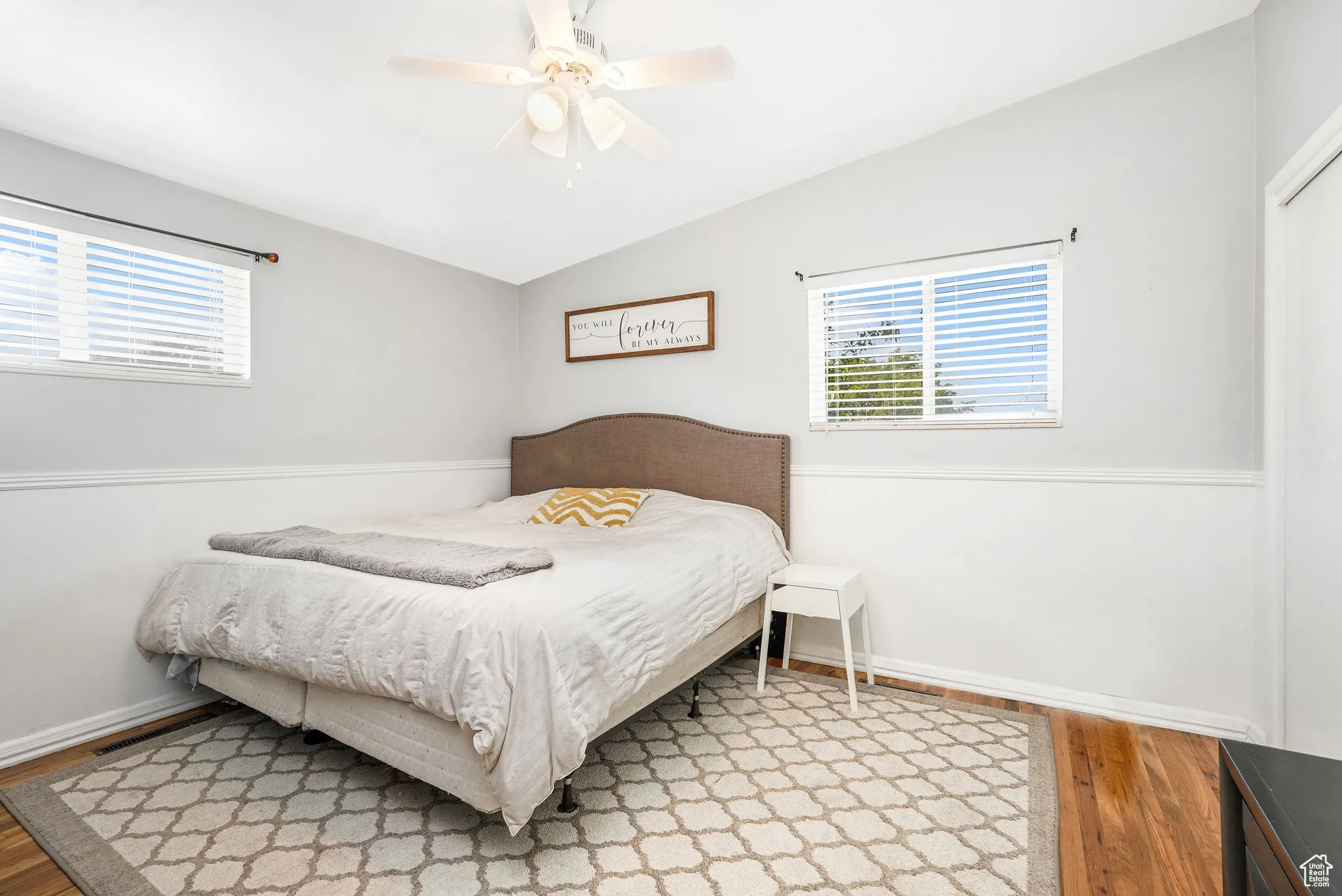 Bedroom featuring light wood-style flooring, multiple windows, a ceiling fan, and vaulted ceiling