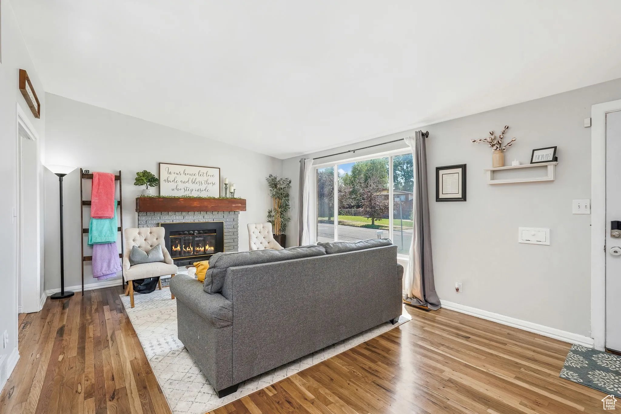 Living room with a stone fireplace and wood finished floors