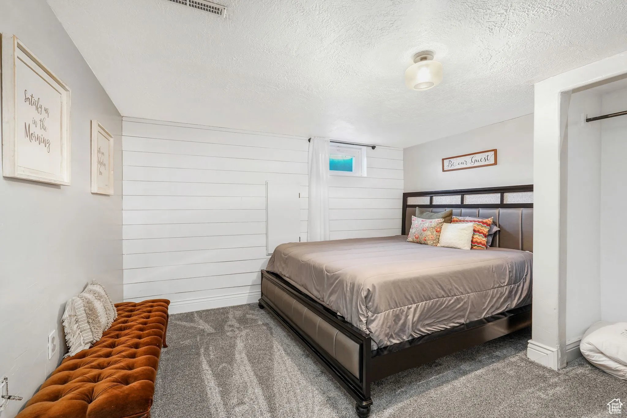 Carpeted bedroom featuring a textured ceiling and wooden walls