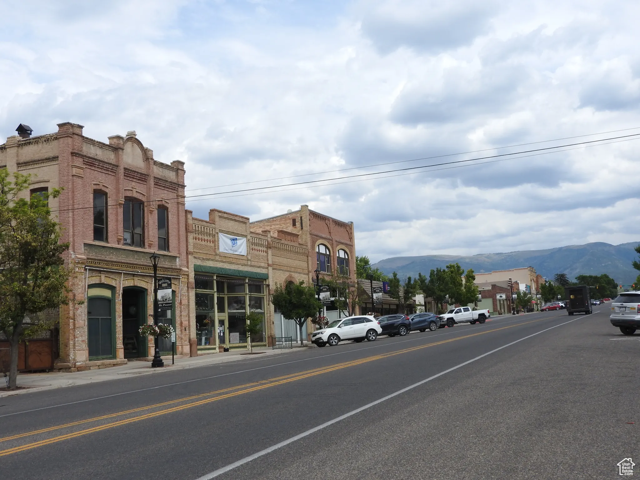 View of asphalt road with a mountain view, sidewalks, and curbs