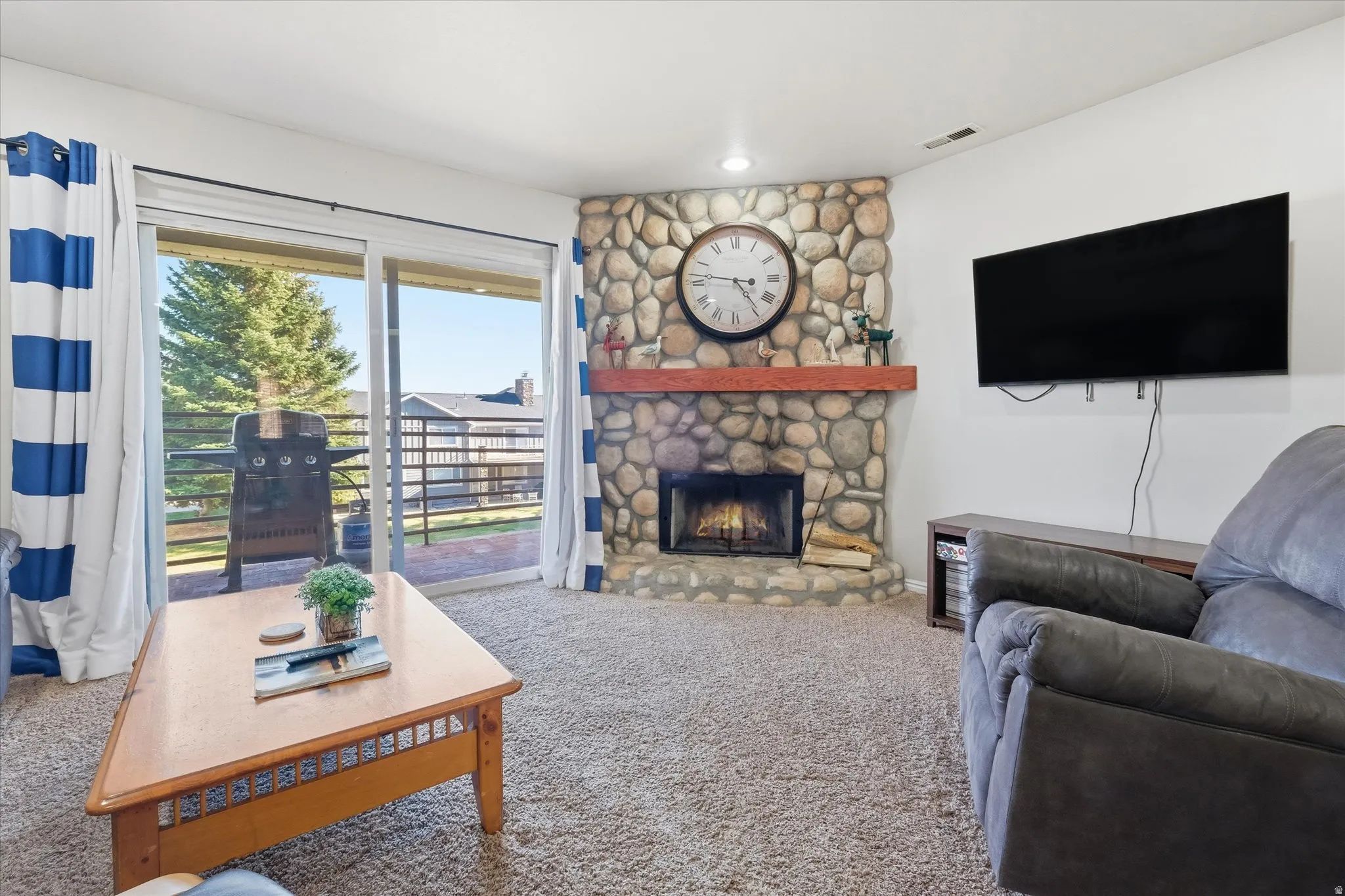 Carpeted living room with a stone fireplace