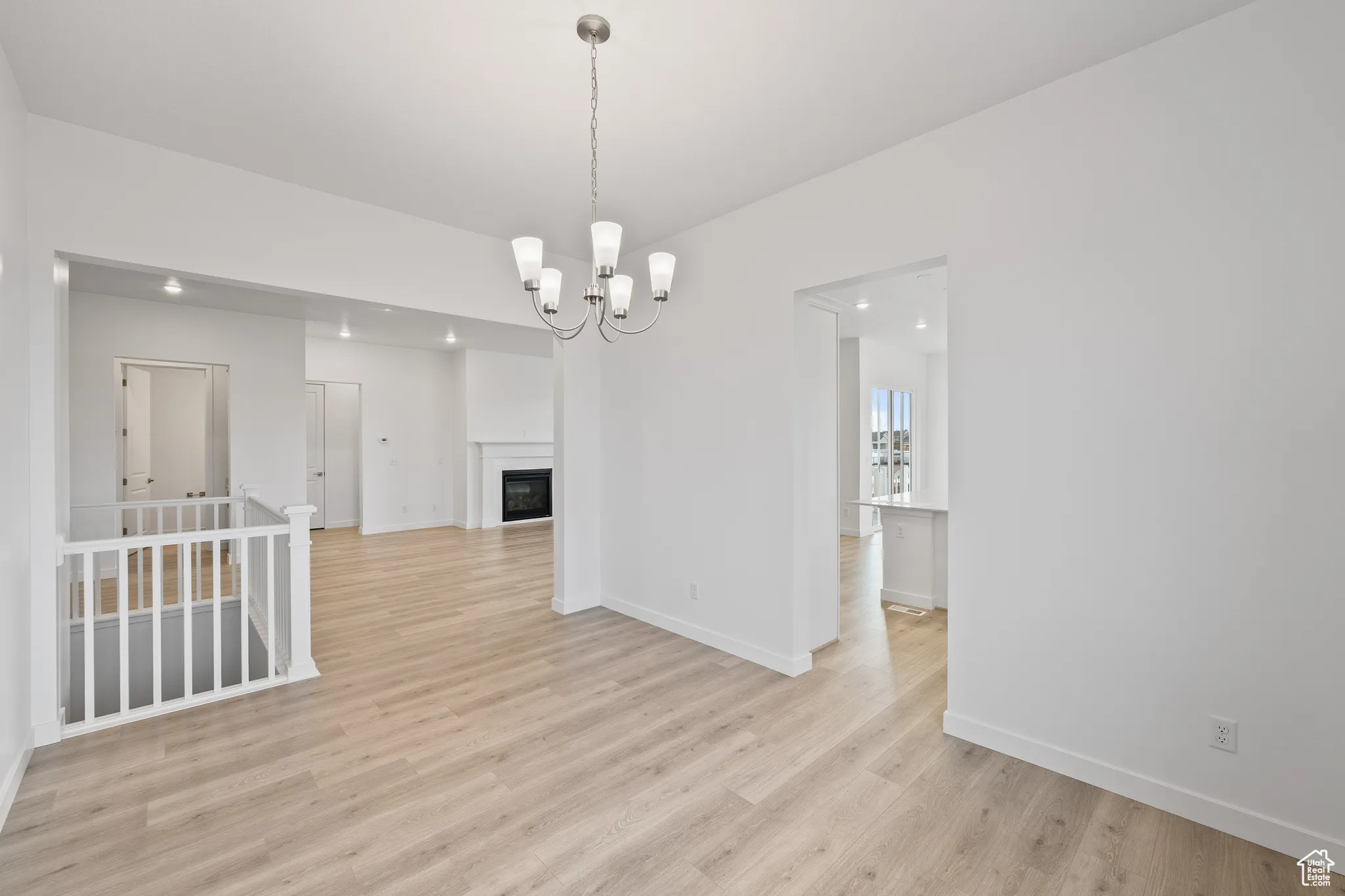 Unfurnished dining area featuring a fireplace, light wood-type flooring, and a chandelier