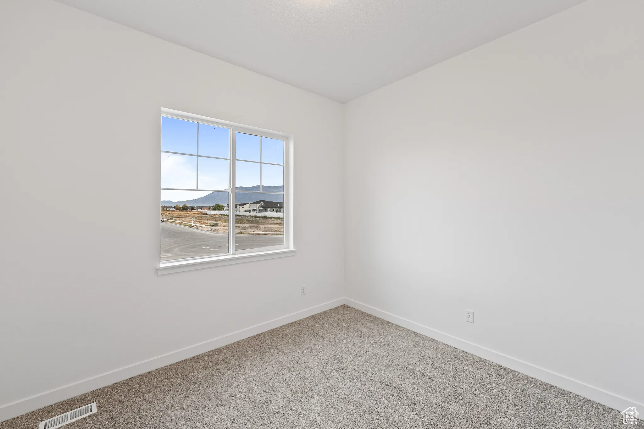 Carpeted empty room with a mountain view and baseboards
