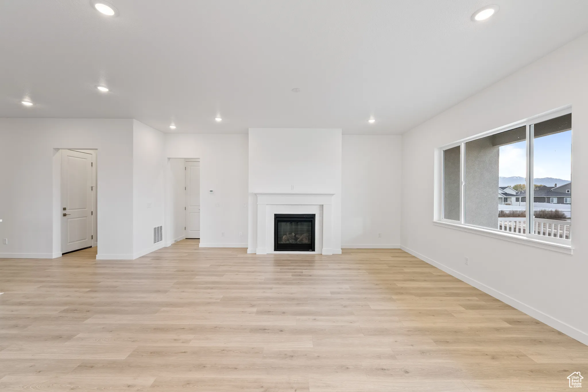 Unfurnished living room with recessed lighting, a glass covered fireplace, and light wood-style flooring