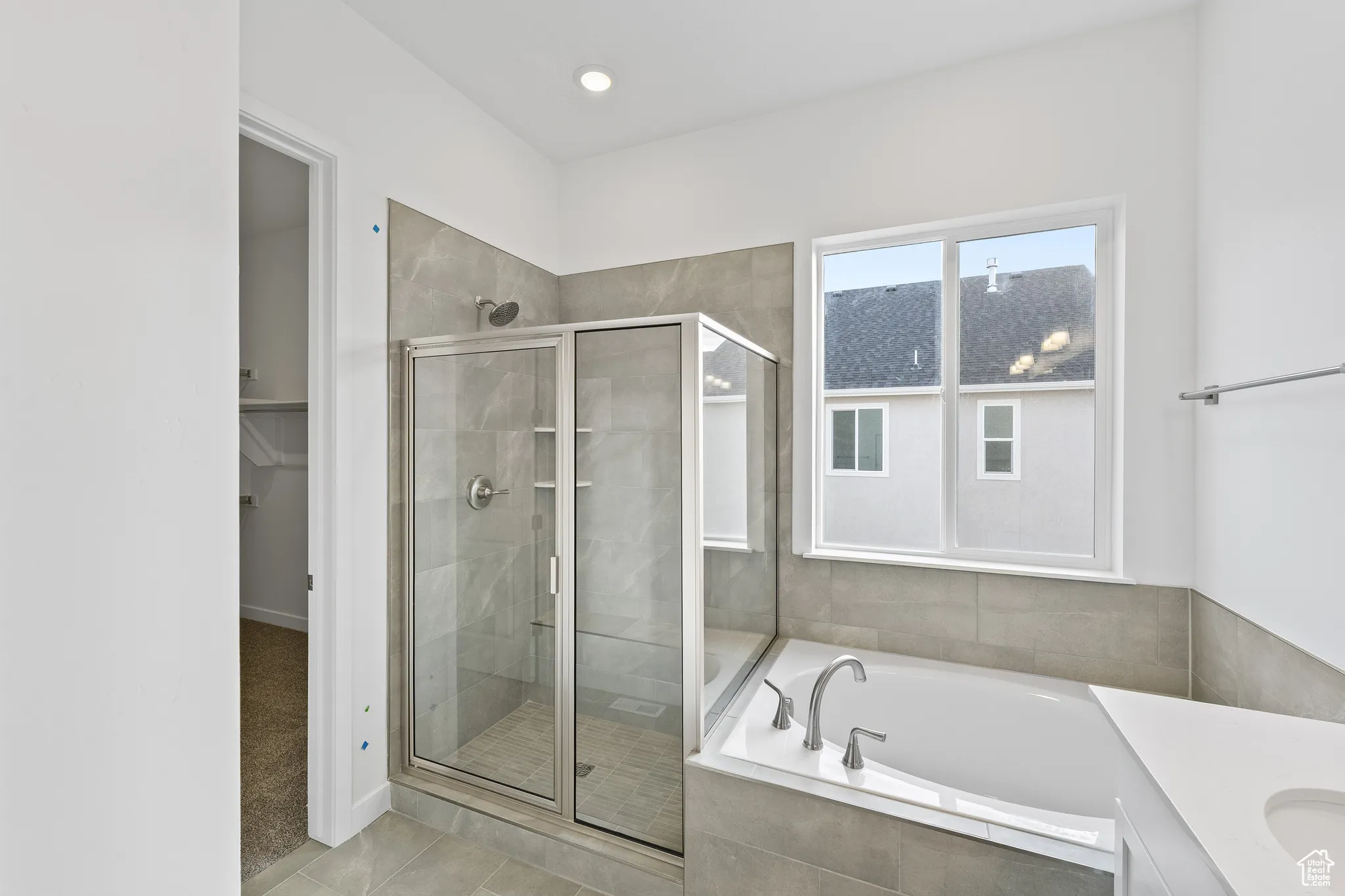 Full bath featuring a bath, vanity, a spacious closet, a shower stall, and recessed lighting