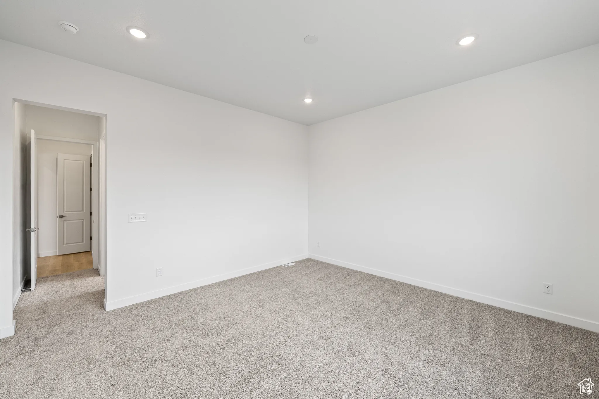 Empty room with light carpet and recessed lighting