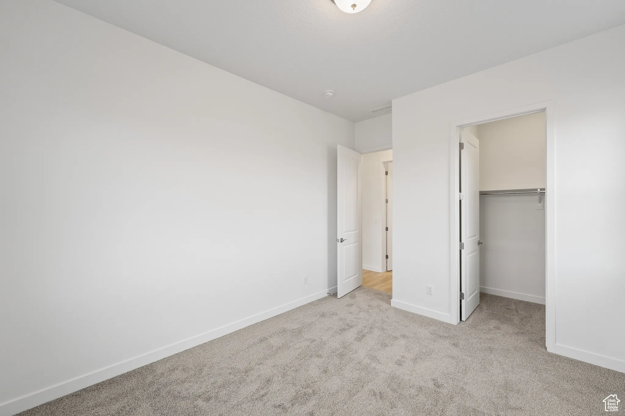 Unfurnished bedroom with a walk in closet and light colored carpet