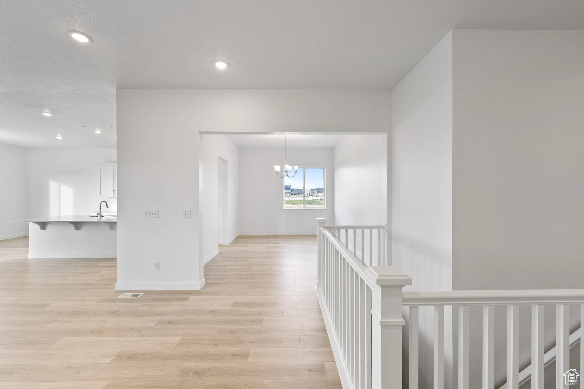 Corridor featuring a chandelier, light wood-style flooring, recessed lighting, and an upstairs landing