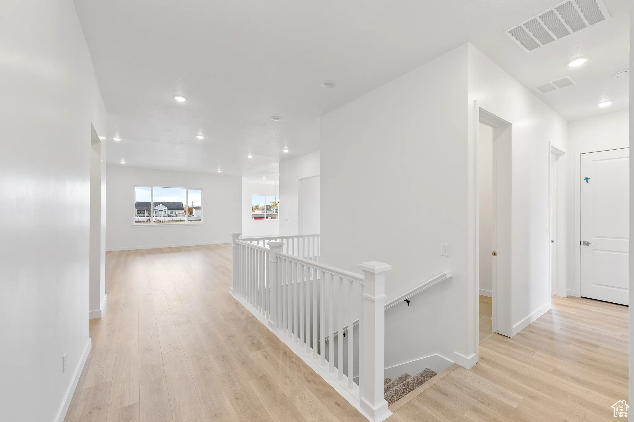 Hallway with an upstairs landing, recessed lighting, and light wood-style flooring