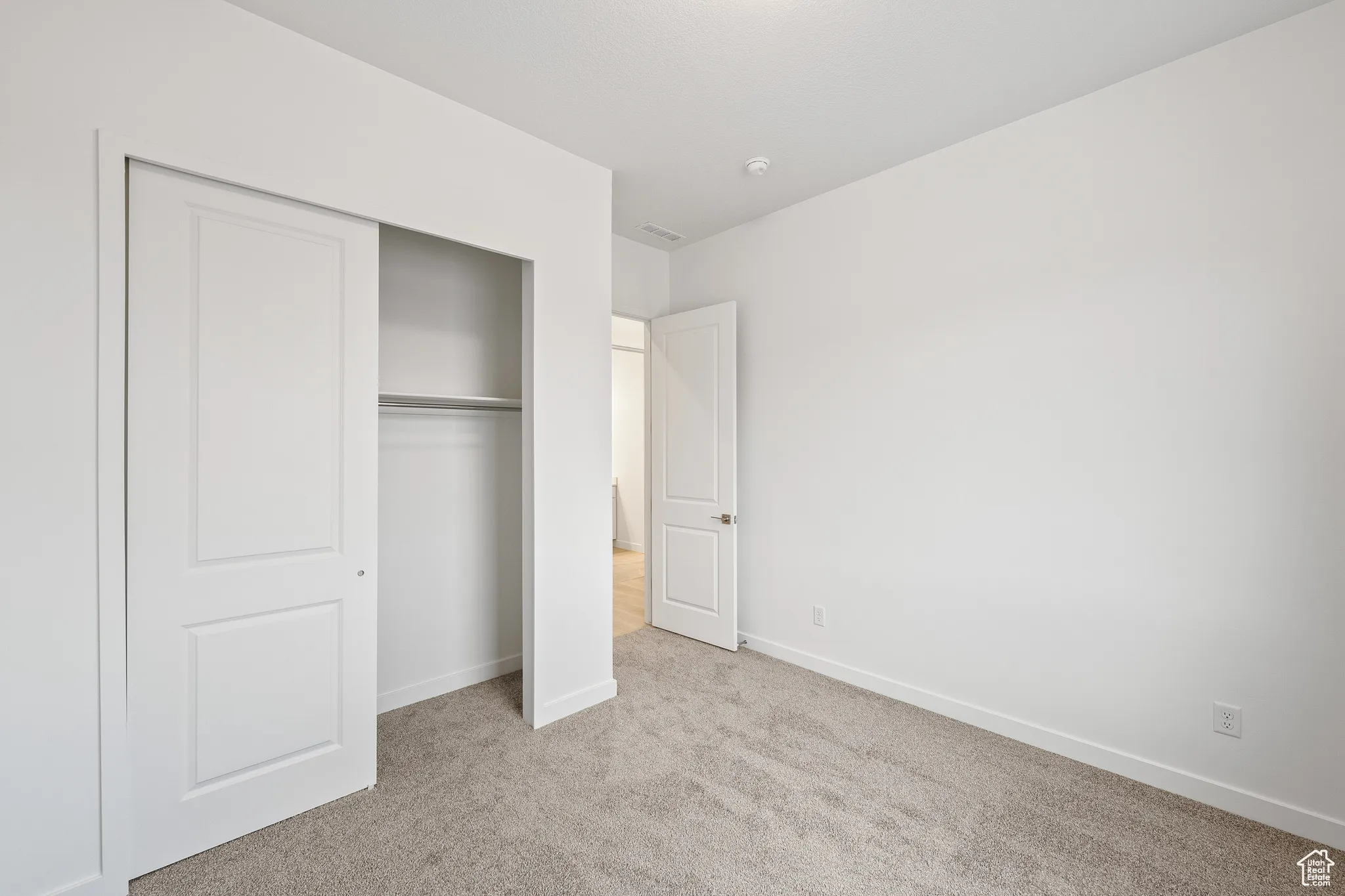 Unfurnished bedroom with light carpet and a closet
