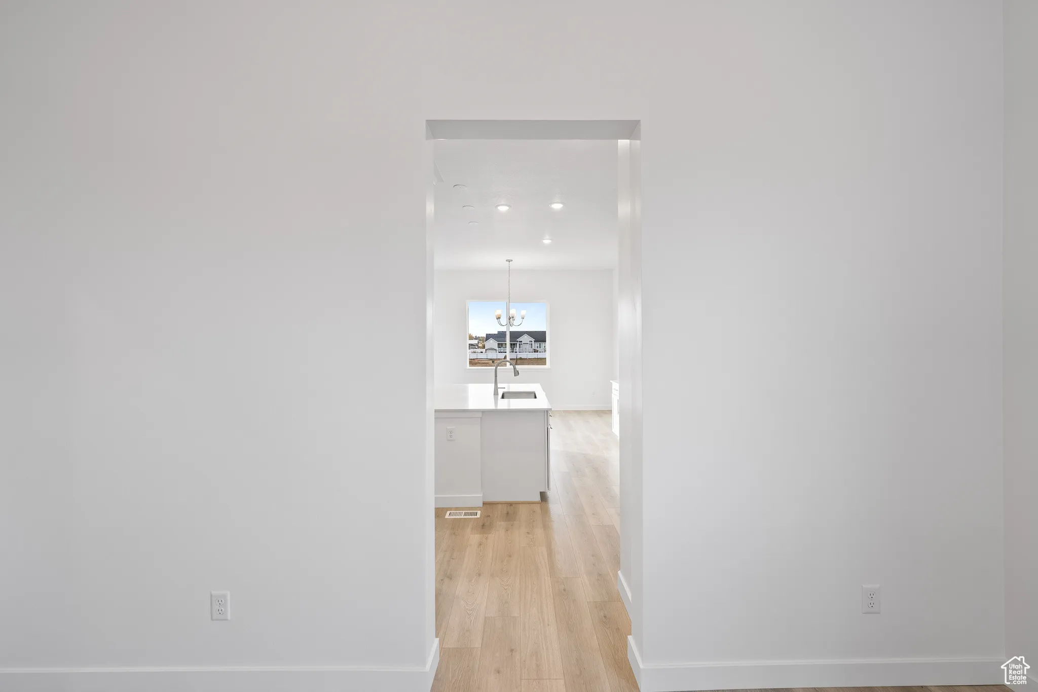 Hall featuring light wood finished floors and a chandelier