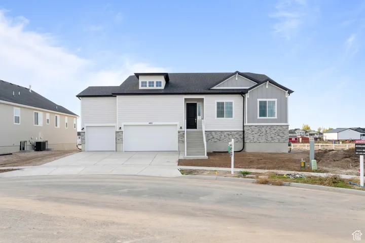 View of front of property featuring stone siding, driveway, an attached garage, board and batten siding, and a shingled roof